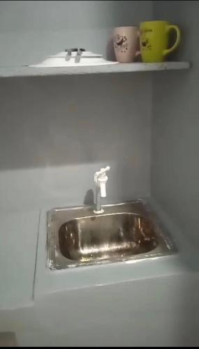 a kitchen sink with two cups on a shelf at Casa Dwayne room 102 in Cebu City