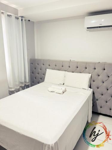 een slaapkamer met een wit bed met een grijs hoofdeinde bij Atria 304 in Tambaú
