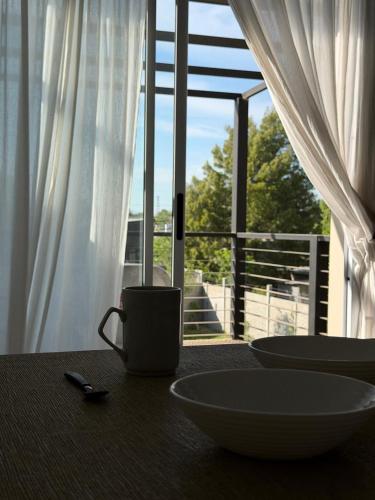 a table with two bowls on a table with a window at Departamentosenchascomus in Chascomús