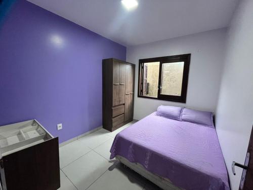 a bedroom with a purple bed and a window at Casa de Praia in Capão da Canoa