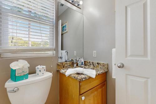 een badkamer met een wastafel, een toilet en een spiegel bij Jewel in the Sea in Duck Key