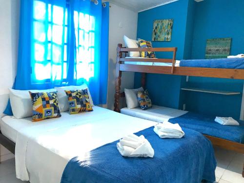 two beds in a room with blue walls at Pousada Turquesa By Gente Bonita in Búzios