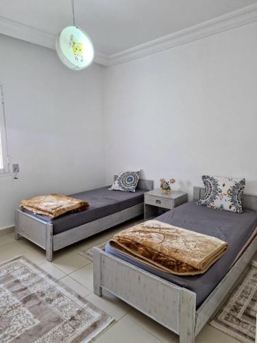 two beds in a room with two tables at Appartement Sousse in Hammam Sousse