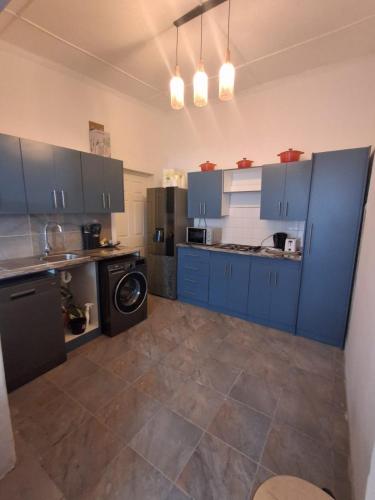 een grote keuken met blauwe kasten en een vaatwasser bij Imany house in Kaapstad