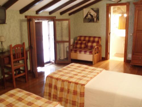 a bedroom with two beds and a table and a chair at Posada Las Puentes in Barcenilla
