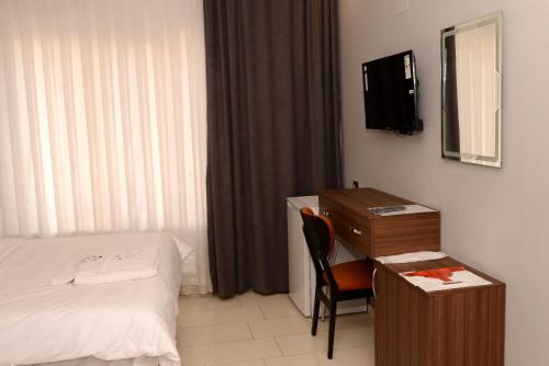 SeyhanNew Sirius Otel的酒店房间内有一张床、一张桌子和一台电视。