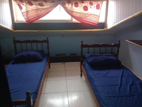 Dos camas en una habitación pequeña con ventana. en Hostel & Cia Itanhaém, en Itanhaém