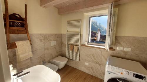 een badkamer met een wastafel en een toilet en een raam bij Casa Mia in Agordo