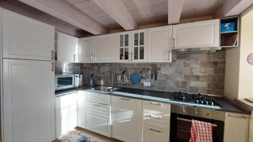 een witte keuken met witte kasten en een spoelbak bij Casa Mia in Agordo