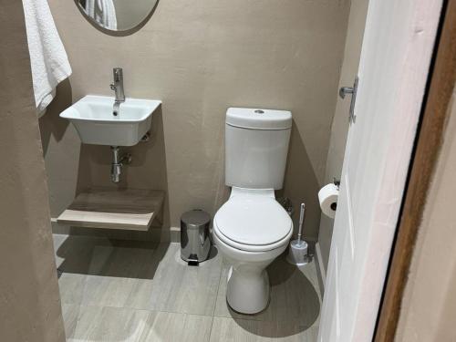 UlundiThe Umbrella Shade的浴室里有白色马桶和洗手池