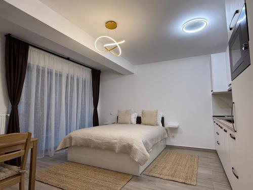 a white bedroom with a bed and a window at The View Studio 2 Busteni in Buşteni