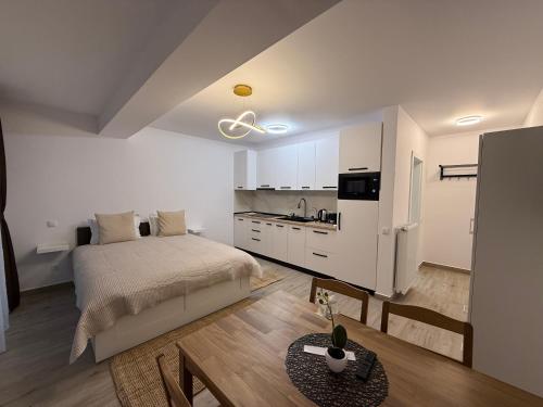 a white bedroom with a bed and a kitchen at The View Studio 2 Busteni in Buşteni