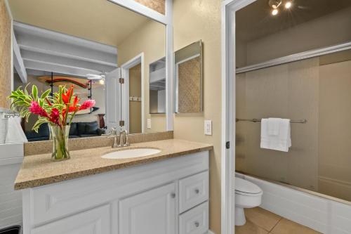 ein Badezimmer mit Waschbecken und einer Blumenvase in der Unterkunft (P9B) 1Br with Loft Princeville Retreat, Pool, AC, Wifi in Puupehu