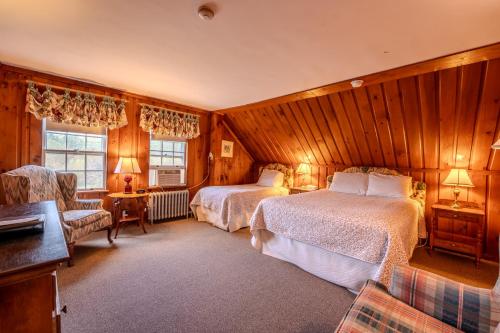 a bedroom with two beds and a couch and a chair at Franconia Inn in Franconia