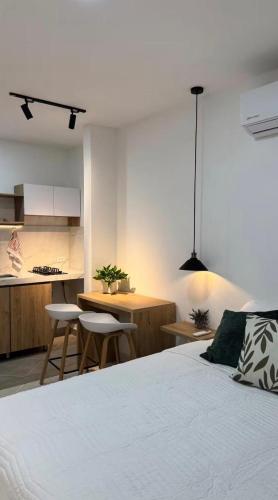 a bedroom with a white bed and a kitchen at Aparta estudio Luxury in Cali
