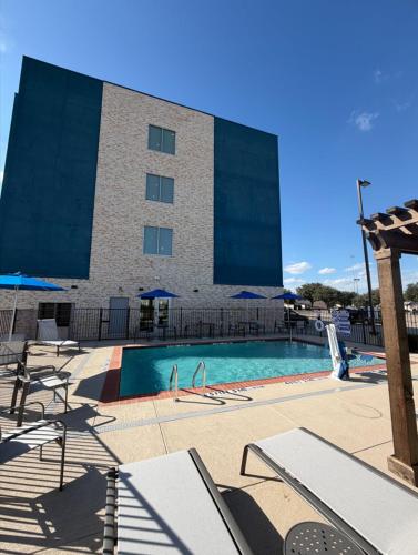 a building with a swimming pool in front of a building at Holiday Inn Express & Suites Dallas - Plano North by IHG in Plano