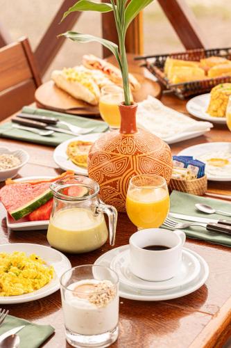 ein Tisch mit Tellern voller Essen und einer Vase darauf in der Unterkunft Hotel Ilha do Marajó by Unna in Soure