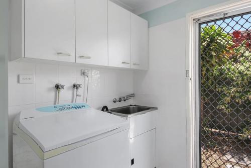 eine weiße Küche mit Spüle und Fenster in der Unterkunft Periwinkle Blue - Pet Friendly, Golden Beach in Golden Beach