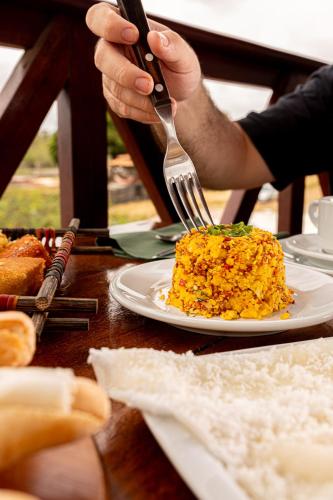eine Person, die eine Gabel über einen Teller mit Essen hält in der Unterkunft Hotel Ilha do Marajó by Unna in Soure