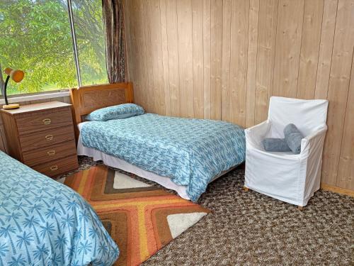 een kamer met twee bedden en een stoel erin bij 3 Barragoot Street in Bermagui