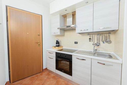 a kitchen with white cabinets and a sink and a door at Bardonecchia Campo Smith 3 in Bardonecchia