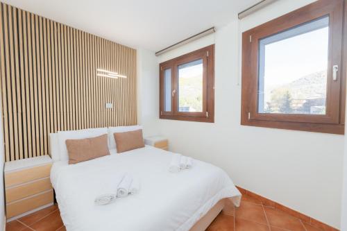 a bedroom with a white bed and two windows at Bardonecchia Campo Smith 3 in Bardonecchia