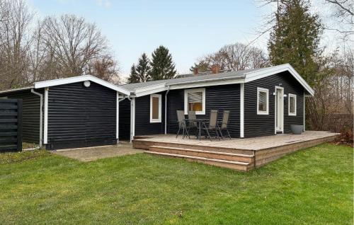 ein kleines schwarzes Haus mit einer Holzterrasse in der Unterkunft Beautiful Home In Dronningmølle With Wifi in Hulerød