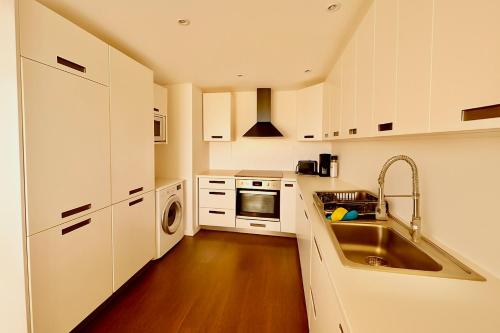 een keuken met witte kasten en een spoelbak bij Douce escale - T3 d exception face mer in Saint-Jean-de-Monts