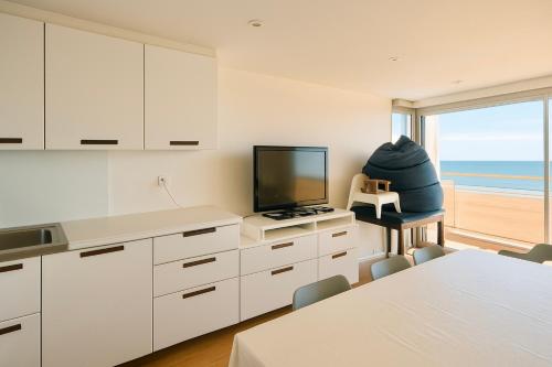 een keuken met een televisie en een tafel met stoelen bij Douce escale - T3 d exception face mer in Saint-Jean-de-Monts