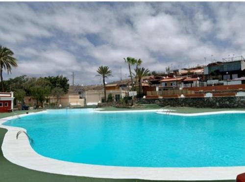 ein großer blauer Pool mit Gebäuden im Hintergrund in der Unterkunft Meloneras Maspalomas Pasito Blanco in Pasito Blanco