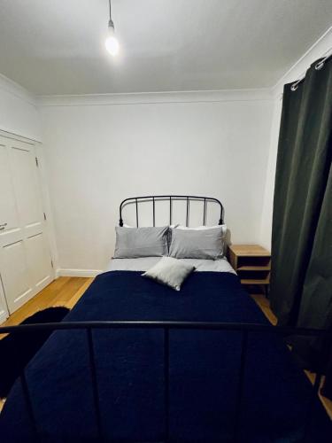 a bedroom with a bed with a blue blanket at Obsidian Room - shared bathroom in Ponders End