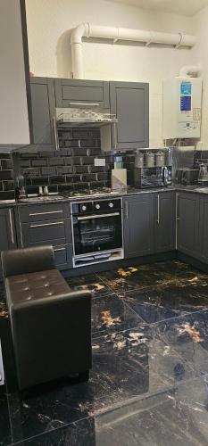 een keuken met een fornuis en een stoel. bij Comfy 2 Bedroom House near City Centre and Uclan in Preston