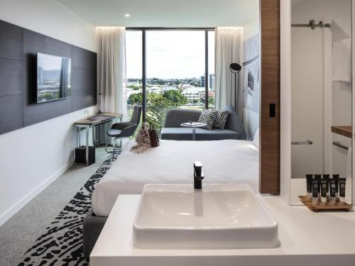 a hotel room with a bed and a sink at Novotel Brisbane South Bank in Brisbane