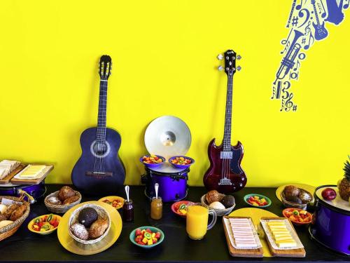 a table with food and two guitars on a wall at Ibis Styles Merida Galerias in Mérida