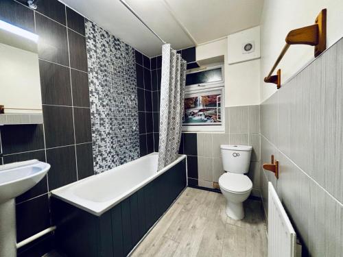 een badkamer met een bad, een toilet en een wastafel bij Midnight Horizon in Ponders End
