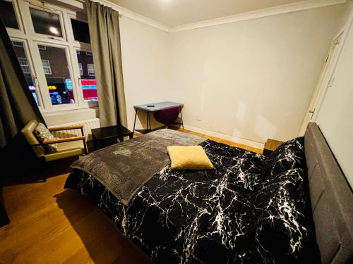 een slaapkamer met een bed, een bureau en een raam bij Midnight Horizon in Ponders End