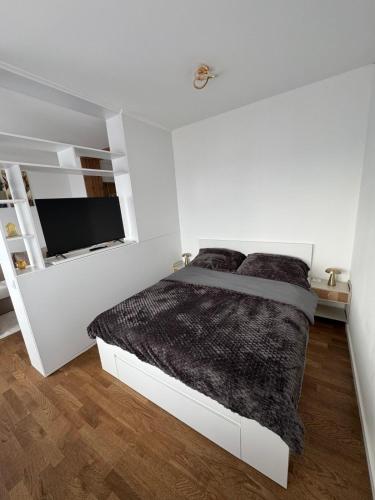 a white bedroom with a bed and a flat screen tv at Cozy apartment Banja Luka in Budžak