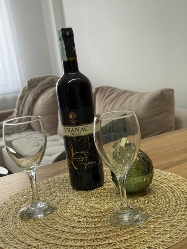 a bottle of wine and two wine glasses on a table at Cozy apartment Banja Luka in Budžak