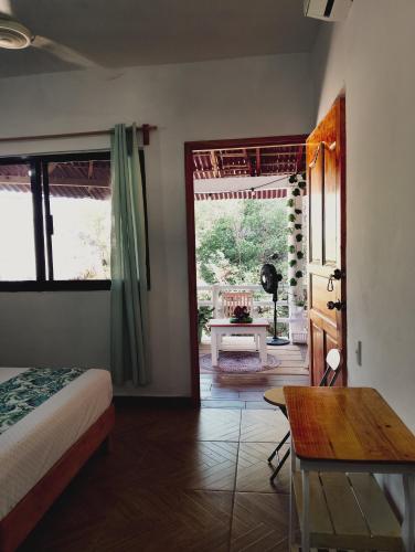 a bedroom with a bed and a table and a door at Posada Casa Tortuga, Zipolite in Zipolite