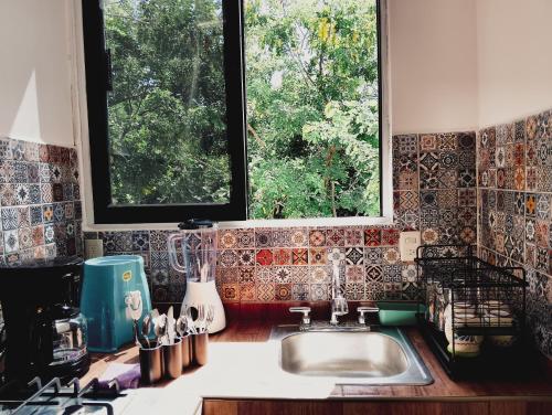 a kitchen counter with a sink and two windows at Posada Casa Tortuga, Zipolite in Zipolite