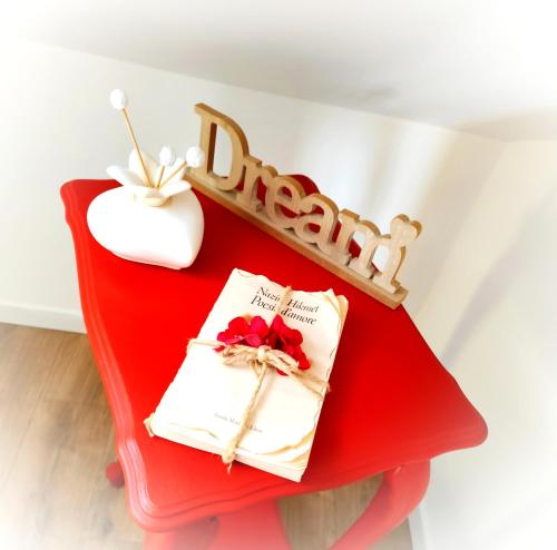 a red shelf with a table with a book and a wooden sign at Le Grenier Apartment in Turin