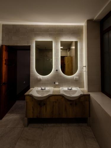 a bathroom with two sinks and two mirrors at Hotel Plaza San Sebastian in Cuenca