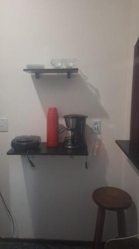 a shelf on a wall with a coffee maker and stool at Panga Loft in Abraão