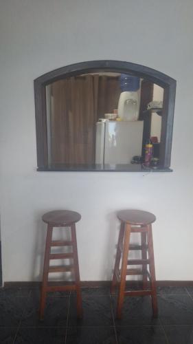 two stools in front of a white wall with a mirror at Panga Loft in Abraão