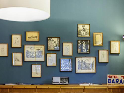 a wall of framed pictures on a blue wall at ibis styles Trani in Trani