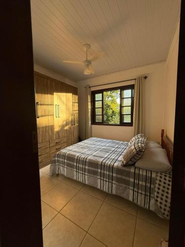 a bedroom with a bed and a window at Interior beach house in Bombinhas! in Bombinhas