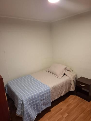 ein kleines Schlafzimmer mit einem Bett mit einer blauen karierten Decke in der Unterkunft M&M Hospedaje in Calama