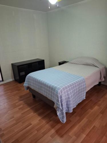 ein Schlafzimmer mit einem Bett mit einer karierten Decke in der Unterkunft M&M Hospedaje in Calama