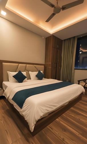 a bedroom with a large white bed with blue pillows at Yatram in Rishīkesh