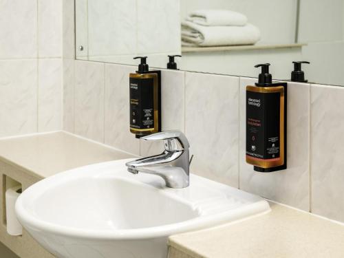 a bathroom sink with two soap dispensers on the wall at The Harlow Hotel By AccorHotels in Harlow